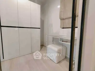 Modern minimalist study room with sleek white furniture and ample storage space.