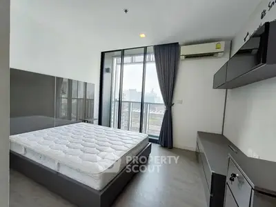 Modern bedroom with large window and city view, featuring sleek furniture and air conditioning.
