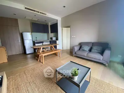 Modern open-layout living room with kitchen, featuring cozy seating and stylish decor.