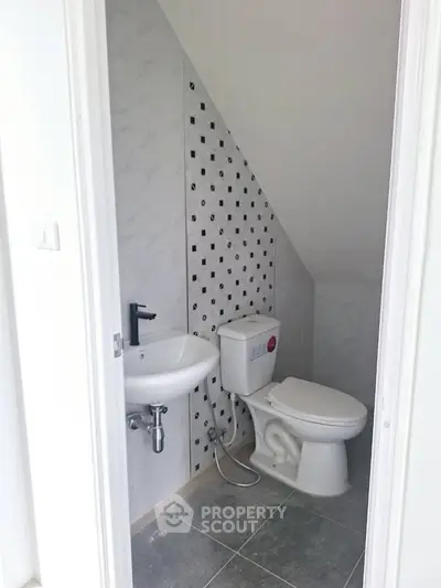 Compact bathroom with modern fixtures under sloped ceiling