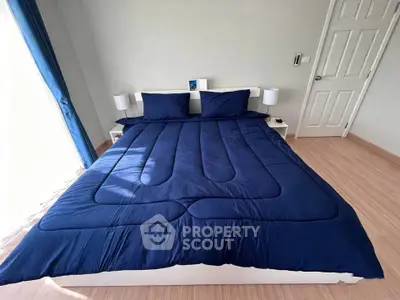 Spacious bedroom with elegant blue bedding and natural light, perfect for relaxation.