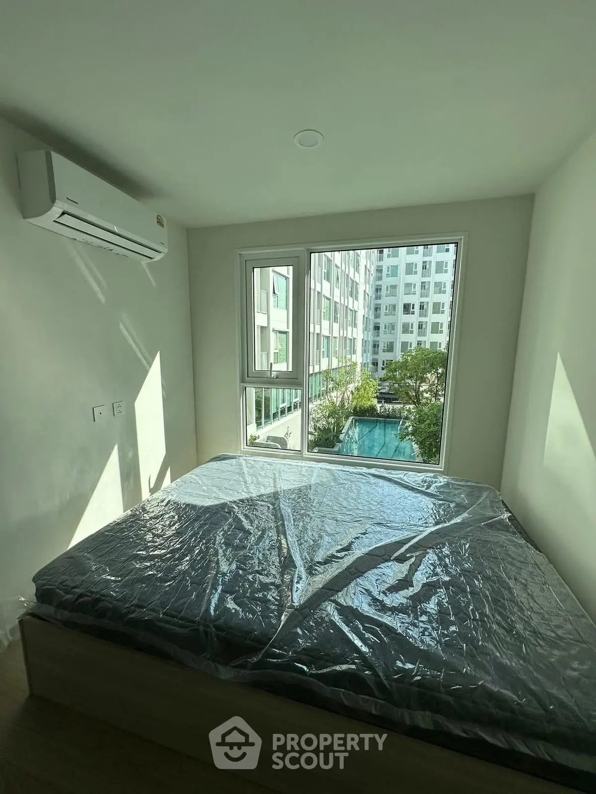 Cozy bedroom with a view of modern apartment complex and pool