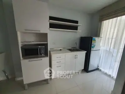 Compact modern kitchen with microwave and fridge in bright apartment