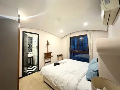 Spacious bedroom with ensuite bathroom and modern decor, featuring large windows and stylish lighting.
