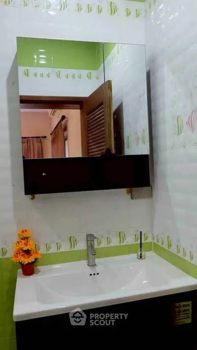 Modern bathroom with stylish mirror cabinet and vibrant green accents