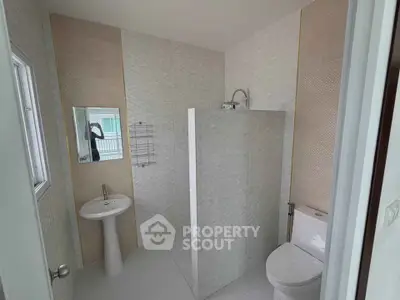 Modern bathroom with sleek design and neutral tones, featuring a pedestal sink and tiled shower area.