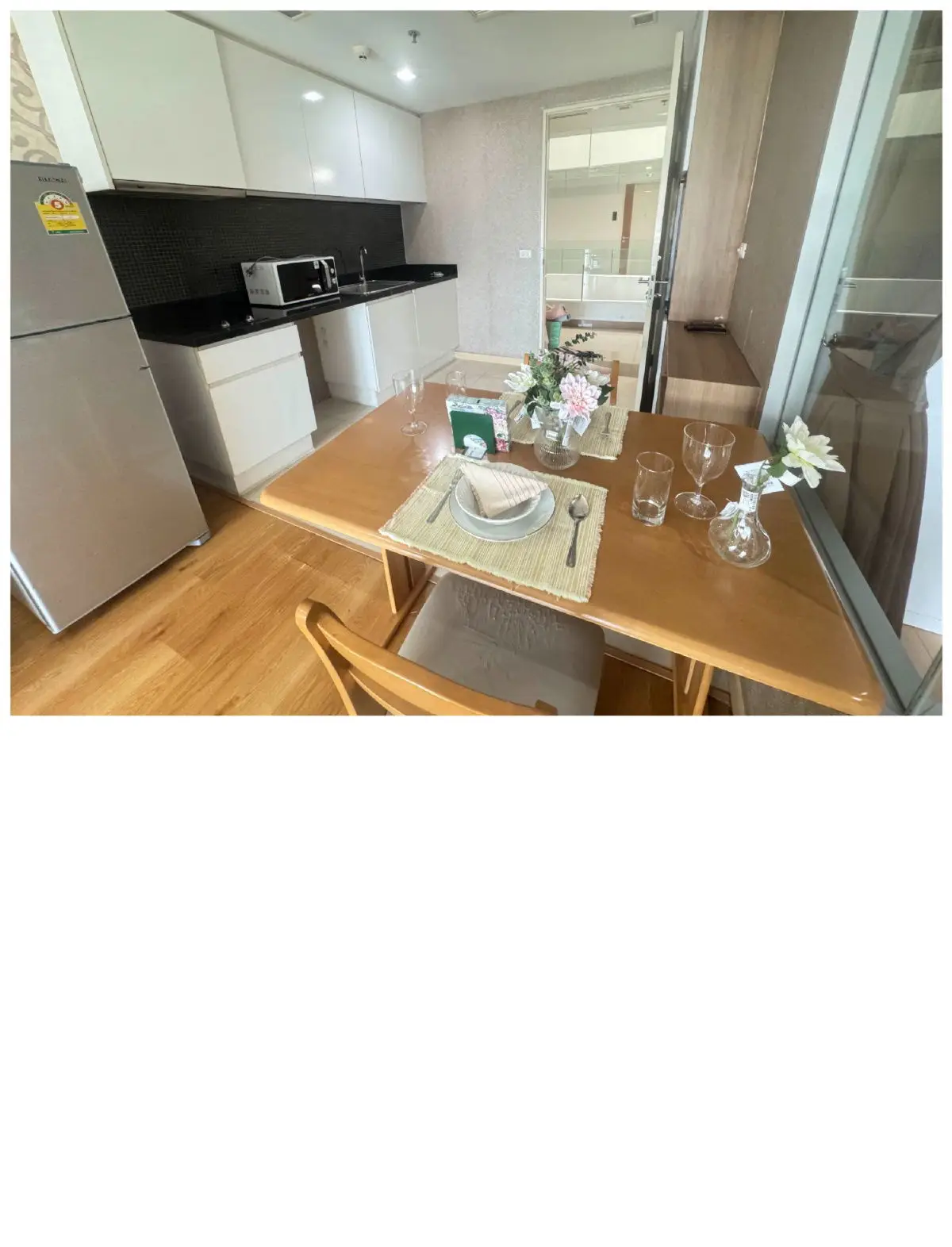 Modern kitchen with dining area, featuring sleek appliances and elegant table setting.