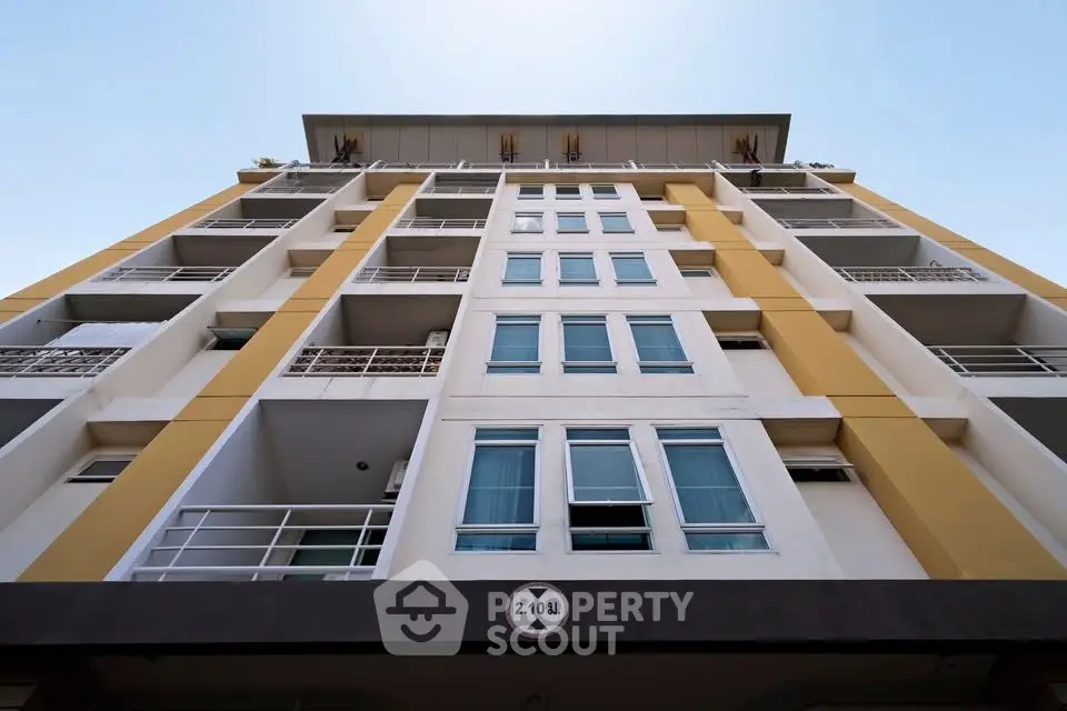 Modern apartment building exterior with balconies and large windows under clear blue sky.