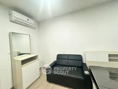 Modern compact living room with sleek black sofa and air conditioning unit