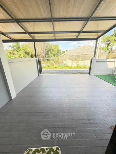 Spacious covered outdoor area with tiled flooring and scenic view, perfect for relaxation.