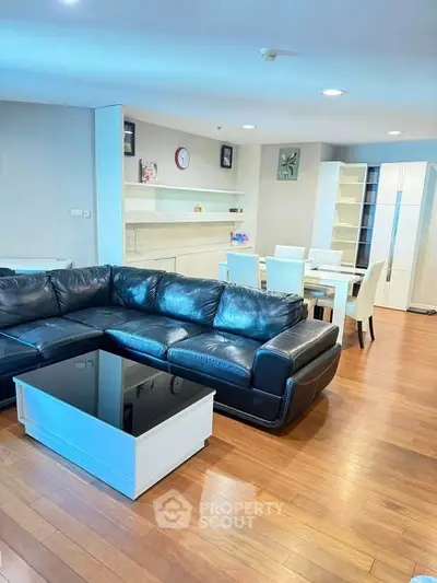 Spacious modern living room with sleek black leather sofa and elegant dining area, perfect for entertaining.