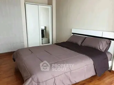 Modern bedroom with sleek design and wooden flooring, featuring a stylish bed and mirrored wardrobe.