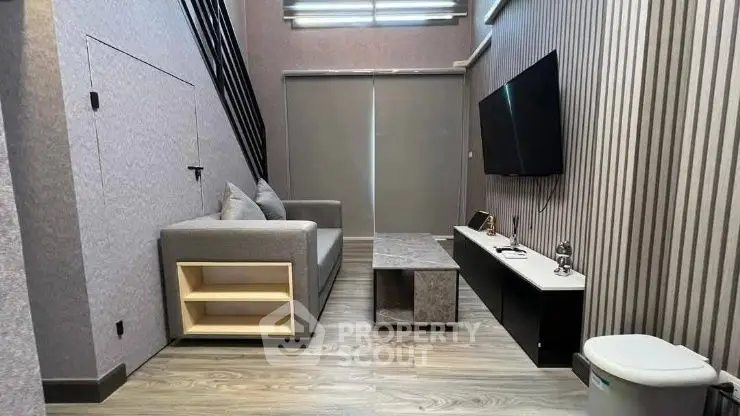 Modern living room with sleek design, featuring a cozy gray sofa, wall-mounted TV, and stylish decor.