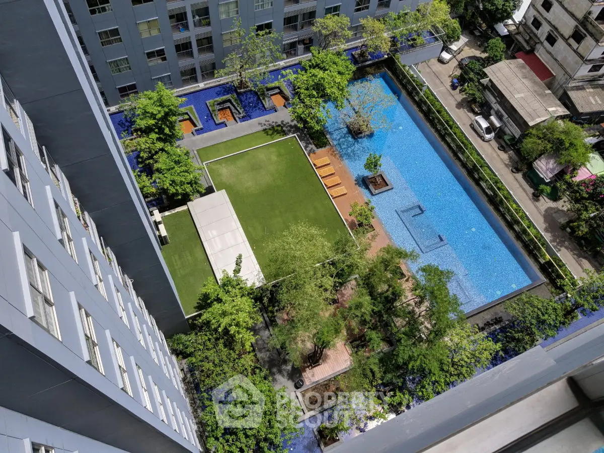 Stunning aerial view of modern apartment complex with lush garden and inviting swimming pool.