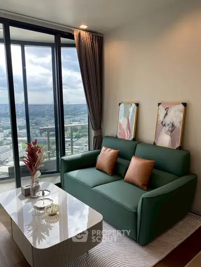 Stylish living room with green sofa, modern decor, and panoramic city view from large windows.