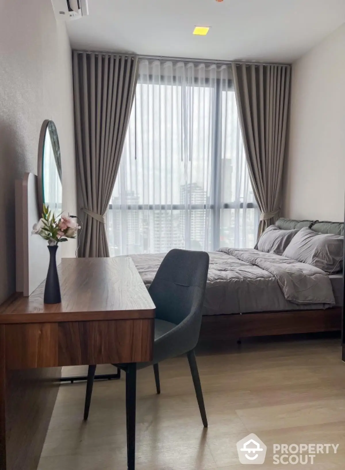 Modern bedroom with elegant decor and city view, featuring a stylish desk and comfortable bed.