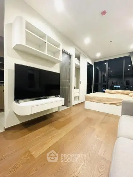 Modern living room with sleek TV setup and cozy bedroom view.
