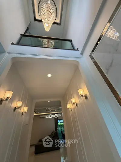 Luxurious high-ceiling hallway with elegant chandelier and modern lighting fixtures
