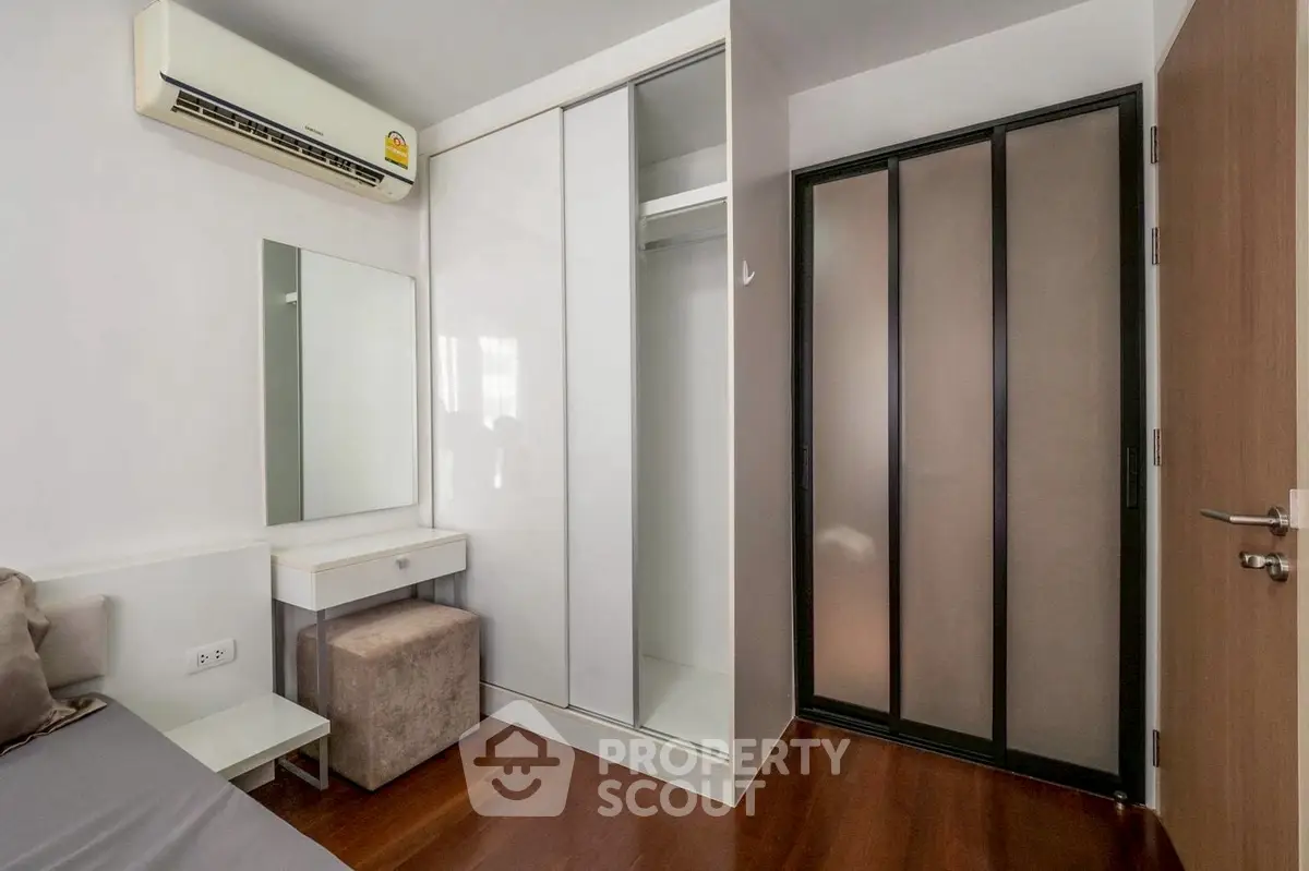 Modern bedroom with sleek wardrobe and air conditioning, featuring a cozy vanity area.
