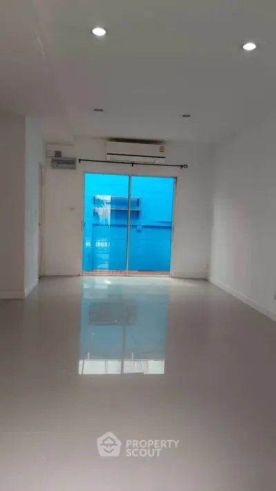 Spacious empty room with glossy floor and large window for natural light.