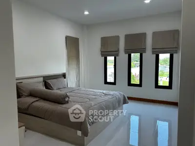 Spacious bedroom with large windows and modern decor, offering serene views and ample natural light.