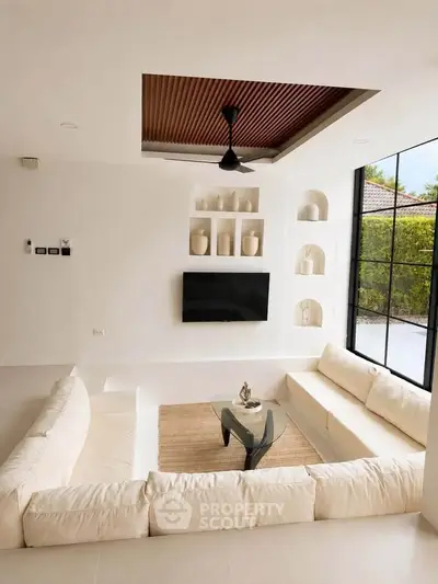 Luxurious sunken living room with modern decor and large windows offering garden views.
