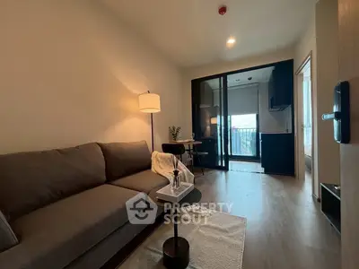 Modern living room with cozy sofa and open layout leading to balcony