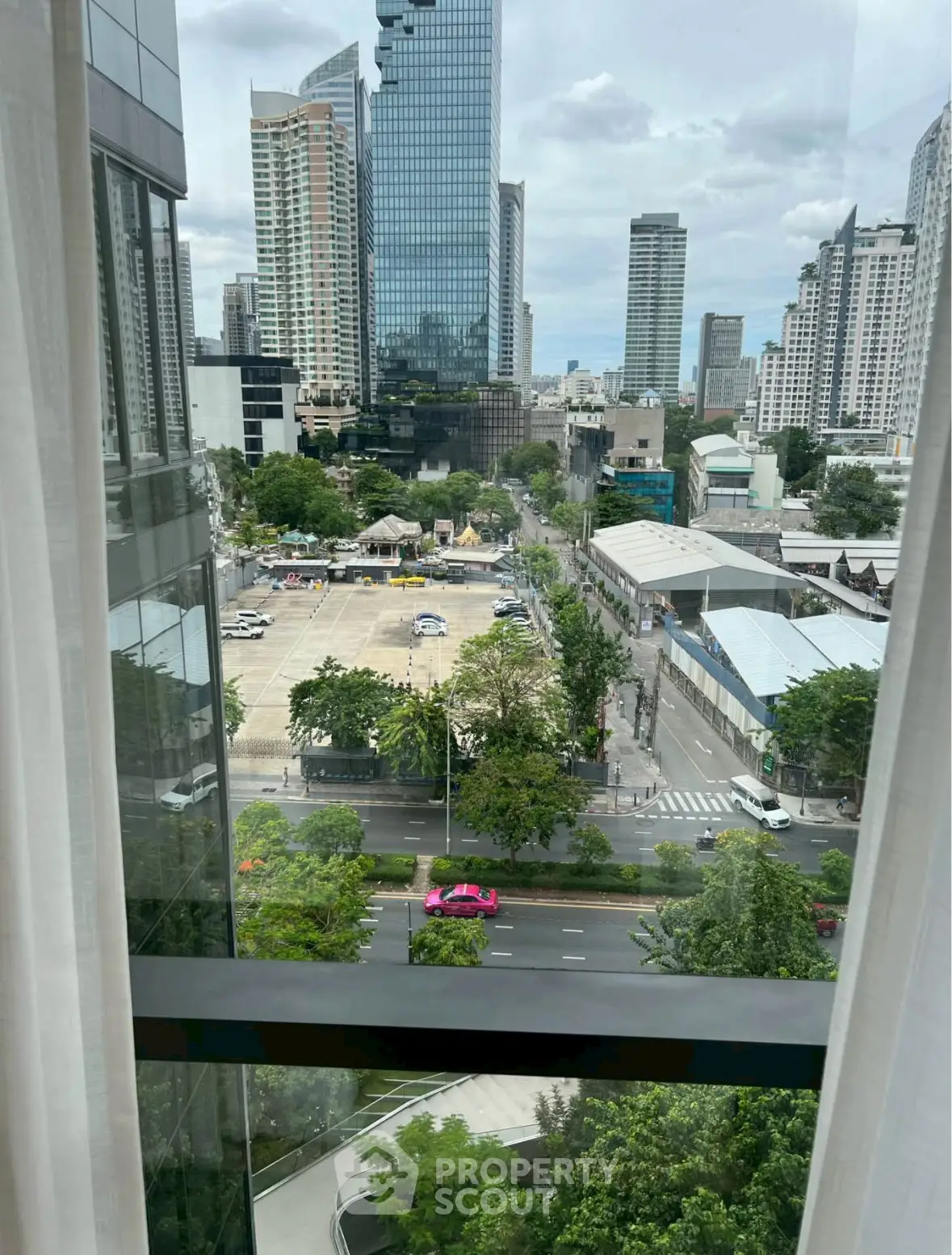Stunning city view from a high-rise apartment window, showcasing urban skyline and vibrant street life.