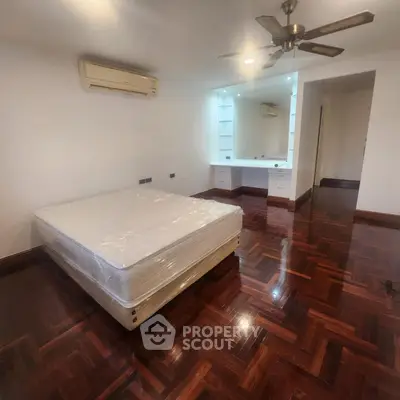Spacious bedroom with wooden flooring and modern ceiling fan