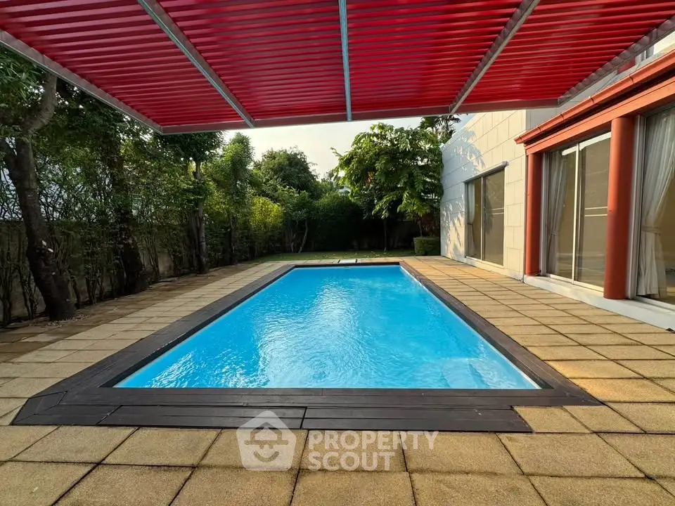 Luxurious private pool with modern red pergola and lush greenery