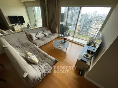 Modern living room with large windows and city view, featuring stylish furniture and wooden flooring.