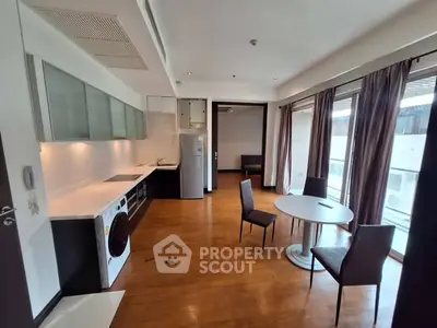 Spacious modern living room with open kitchen and dining area, featuring hardwood floors and large windows.