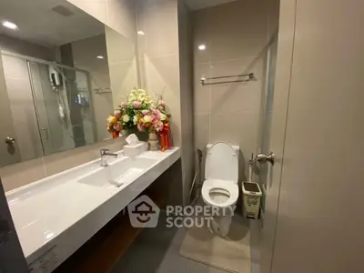 Modern bathroom with sleek fixtures and elegant floral arrangement, perfect for a stylish home.