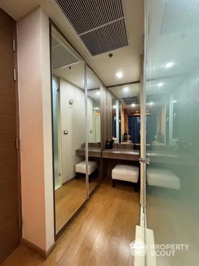 Stylish modern dressing area with mirrored closet and wooden flooring