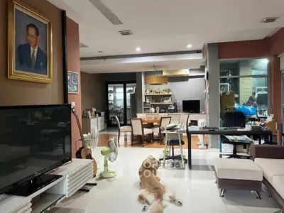 Spacious living room with modern decor and a cozy atmosphere, featuring a large TV and comfortable seating.