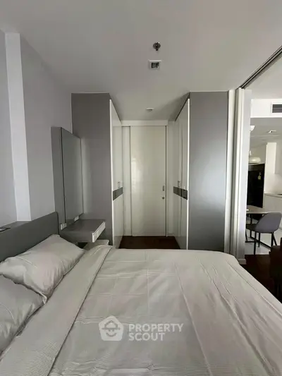 Modern bedroom with sleek design and neutral tones, featuring a comfortable bed and built-in wardrobe.