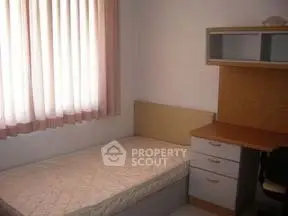 Cozy bedroom with single bed and study desk, perfect for students or professionals.
