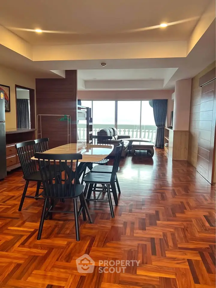 Spacious living room with elegant parquet flooring and stunning ocean view balcony.