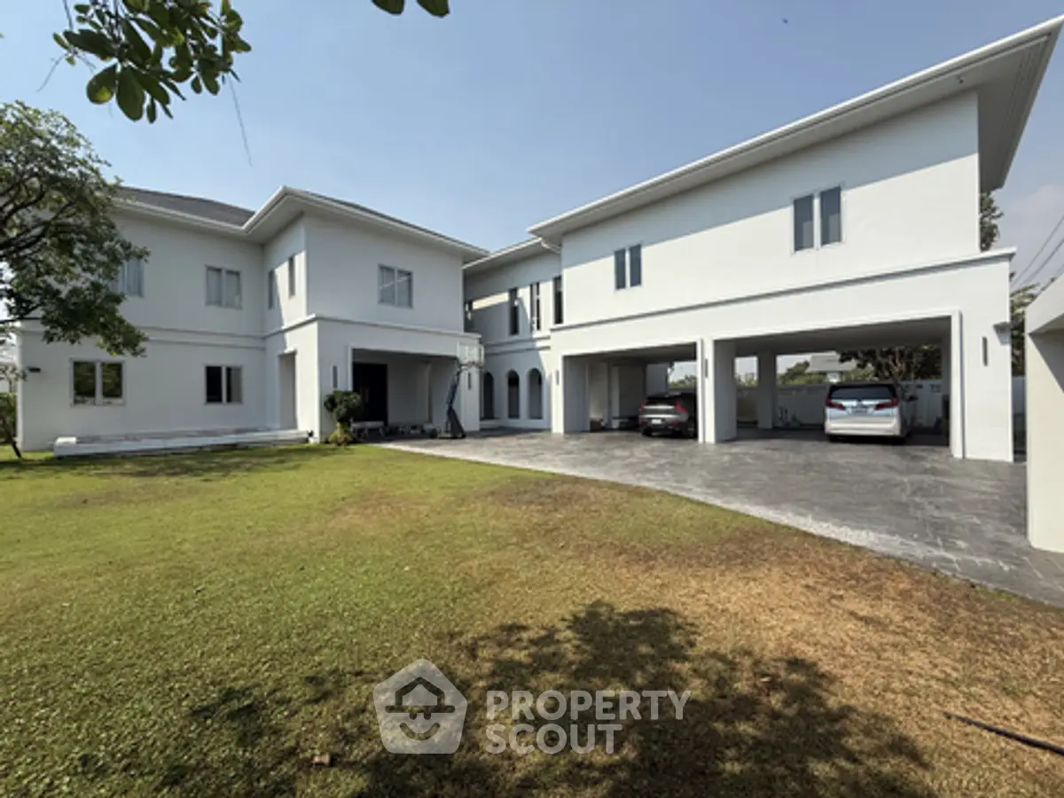Spacious modern white house with large driveway and lush green lawn, perfect for family living.