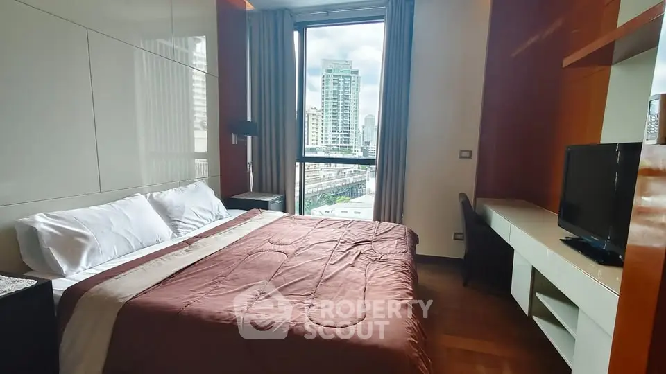 Modern bedroom with city view, featuring a cozy bed and sleek furnishings.
