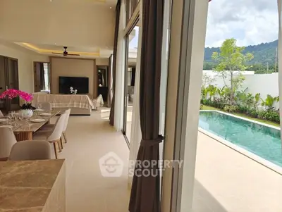 Luxurious open-plan living room with pool view, elegant dining setup, and modern decor in a serene setting.