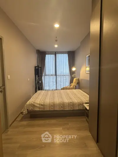 Cozy bedroom with modern decor and large window offering natural light