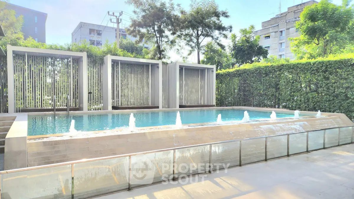 Luxurious modern pool with water features and lush greenery in urban setting.