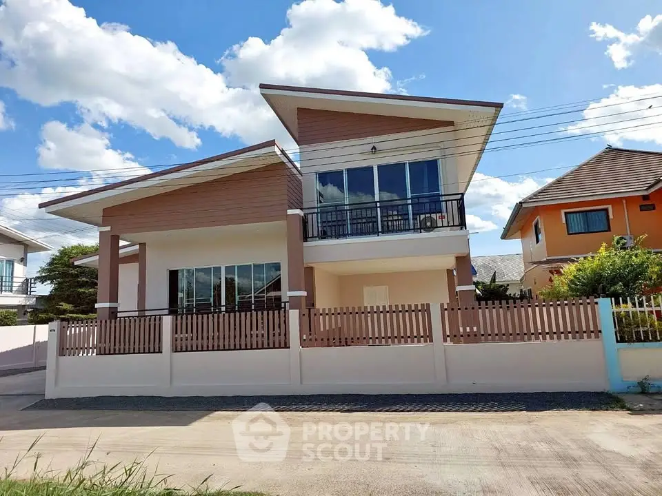 Modern two-story house with unique roof design and spacious balcony, perfect for family living in a serene neighborhood.