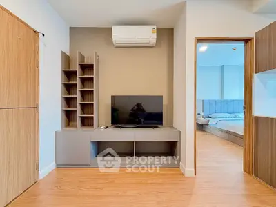 Modern living room with sleek TV unit and view into cozy bedroom