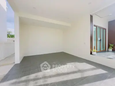 Spacious modern patio with sleek tile flooring and large glass doors, perfect for outdoor relaxation.