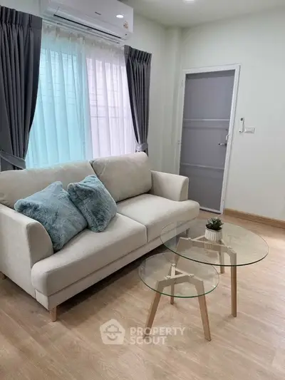 Modern living room with cozy sofa and stylish glass coffee tables, perfect for relaxation.