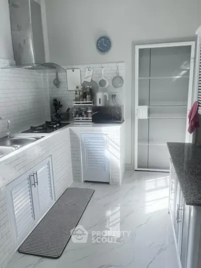 Modern kitchen with sleek white cabinetry and marble flooring