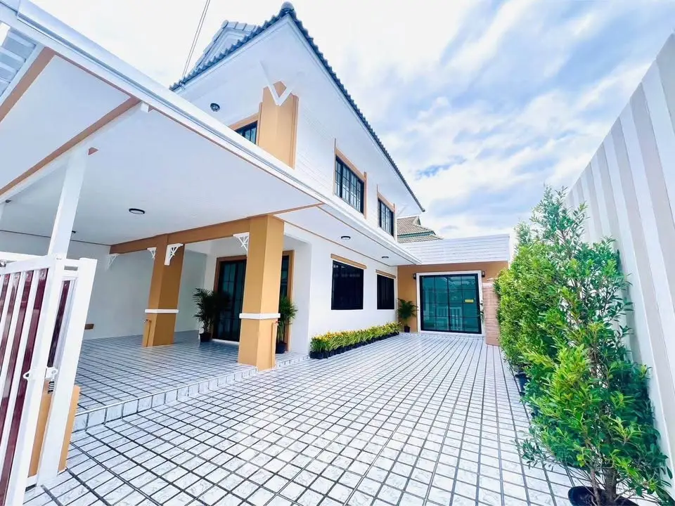 Stunning modern house exterior with spacious tiled driveway and lush greenery.