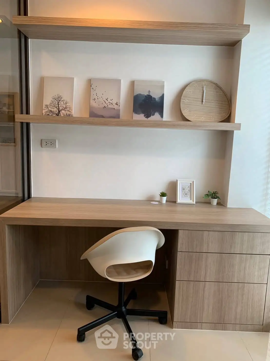 Modern study area with sleek wooden desk, stylish chair, and decorative shelves in a contemporary home.
